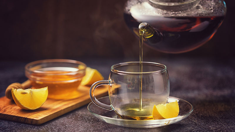 Chávena de chá de limão com tigela de mel ao lado